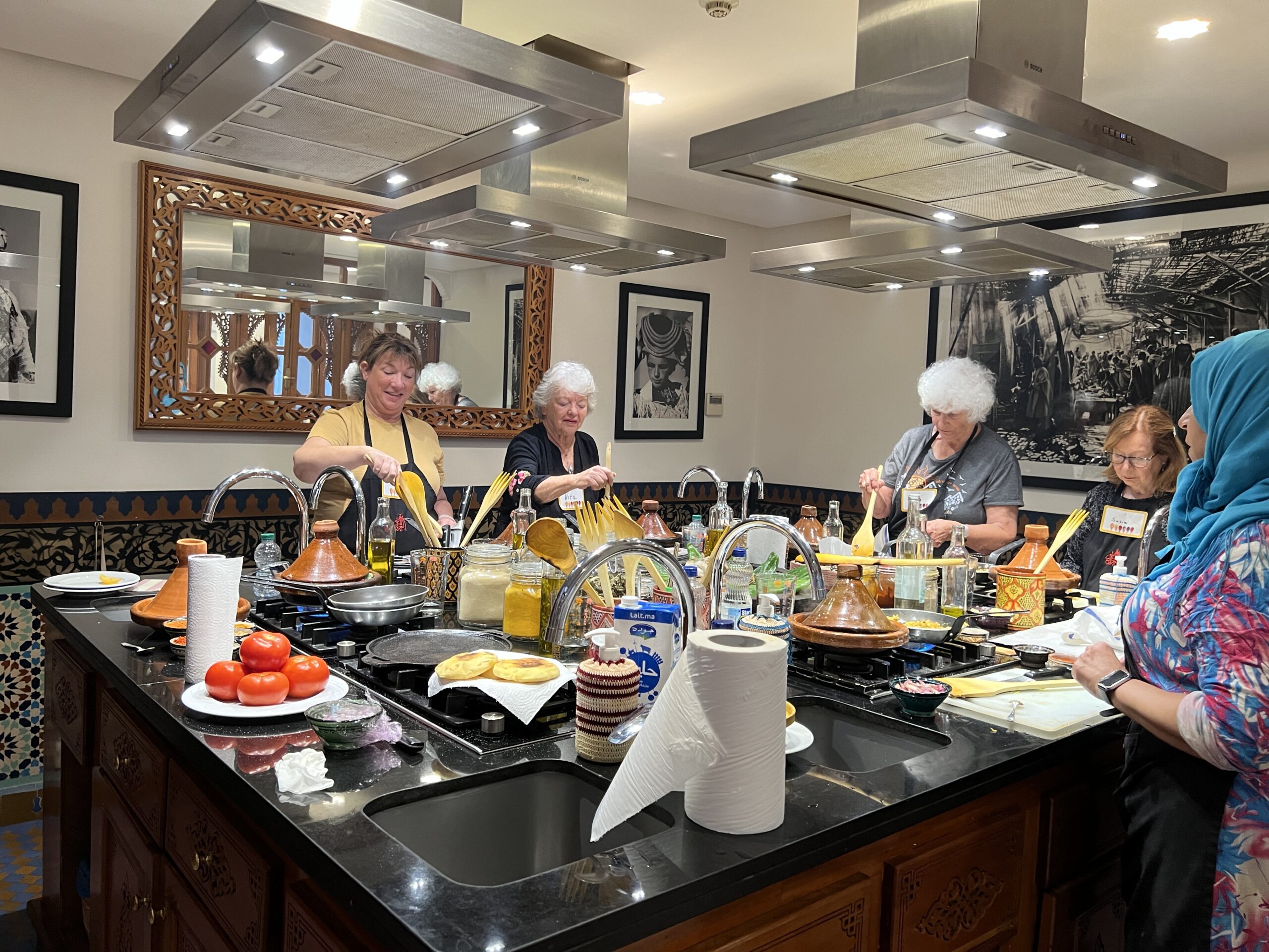 Group of travelers learning traditional cooking in Morocco in a bright, friendly kitchen.